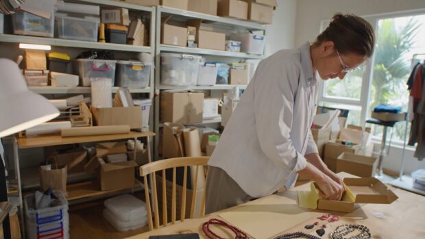 Small business owner preparing handmade products for shipment in a home-based workspace