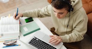 A student studies with a laptop and books, exploring different educational platforms for learning