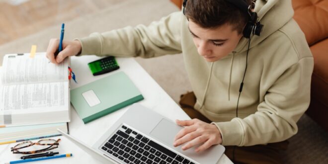 A student studies with a laptop and books, exploring different educational platforms for learning
