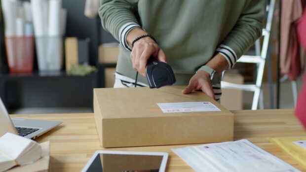 Worker scanning a barcode label on a parcel box using a wireless scanner