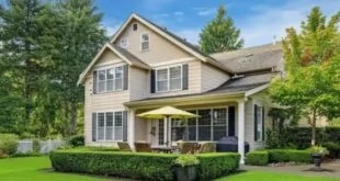 A charming home surrounded by a lush lawn and several trees