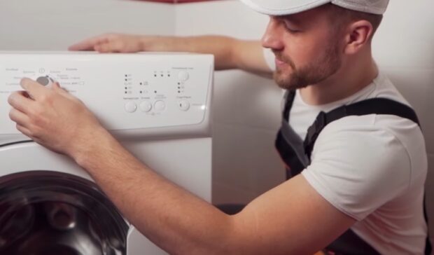 Technician adjusting the cycle settings on a front-loading washing machine control panel