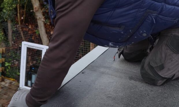 Roofer installing a new flashing strip on a flat roof surface